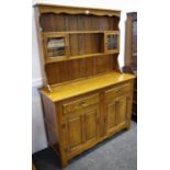 A modern oak dresser, shaped frieze, two glazed door cupboards and shelving to top,