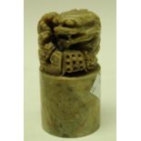 A Chinese soapstone desk weight, carved temple guardian lion on cylindrical base,