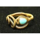 An unmarked gold coloured metal snake signet ring, set with a single polished turquoise blue stone,