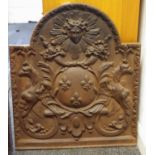 A cast iron fire back decorated in relief with Medusa mask, fanciful dragons and fleur de lys,