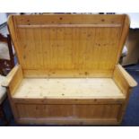 A pine settle, high wing back, hinged seat enclosing storage, 121.5cm high x 12cm wide x 54.