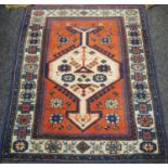 A hand woven Turkish Kozak throw rug, geometric designs in cobalt salmon and cream on a red ground,