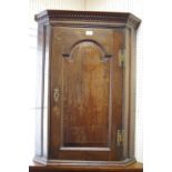 A George III oak corner cabinet, dentil frieze, canted front,