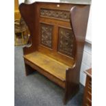 An oak wingback settle, rosette carved panels to back, hidden drawer to seat. 145cm high x 108.