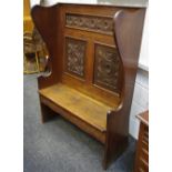 An oak wingback settle, rosette carved panels to back, hidden drawer to seat. 145cm high x 108.