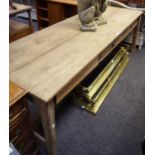 A large salvaged farmhouse pine trestle table with three drawers to one side in frieze