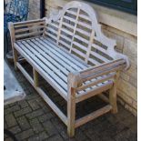 A Lutyens style wooden garden bench, cresting top rail, scrolling arms.