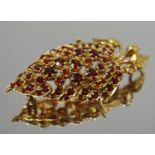A 9ct gold and garnet brooch in the form of a stylised strawberry and foliage, hallmarked, 10.