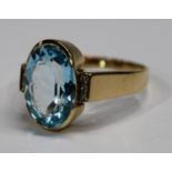 A high carat yellow gold dress ring, set with a central faceted pale blue stone, the shoulders