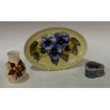 A Moorcroft Pansy pattern oval tray, 23cm wide; an Anemone pattern trinket pot and cover; a small