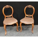 A pair of Victorian mahogany side chairs, each with a looping acanthus, stuffed over upholstery,