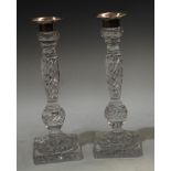 A pair of glass candlesticks, with plated nozzles and sconces, wrythen columns, spreading circular