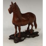 A Japanese hardwood carving, of a horse, standing four square, carved and pierced stand