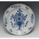 An early 18th century English Delft circular charger, painted in underglaze blue with a Baroque