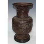 A Chinese brown-patinated bronze baluster vase, cast in relief with ferocious dragons and scroll