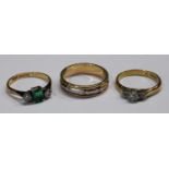 An 18ct gold emerald and diamond ring, 2.4g; an 18ct gold band, 5g; an 18ct gold diamond three stone