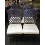 A set of four tubular steel dining chairs, metal lattice work back, padded seat, goat hoof feet to