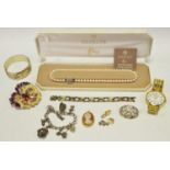 A silver charm bracelet with 8 charms 46.6g; a silver brooch 6.9g; 9ct gold heart shaped locket 0.