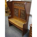 An oak wingback settle, rosette carved panels to back, hidden drawer to seat. 145cm high x 108.5cm