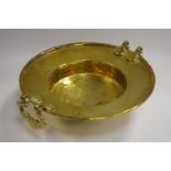 A 19th century brass offertory bowl, twin batwing drop handles raised on tripod feet