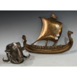 A pewter ram's mask wall hanging, 20cm high; a brass Viking ship wall decoration, 42cm wide (2)