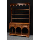 A mid 20th century oak dresser, the plate rack with outswept cornice above a shaped frieze, open