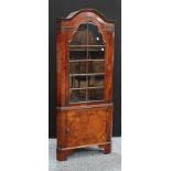 A George III style walnut corner cupboard, dome top above a glazed door inclosing adjustable