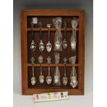 A set of thirteen Rolex base metal teaspoons, a wooden spoon rack