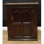 A George III oak cupboard, outswept cornice above two rectangular panel doors, enclosing shaped