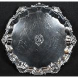 A George II silver shaped circular card waiter, fluted shell border, crested field, hoof feet, 18.