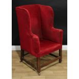A 19th century mahogany wingback armchair, stuffed over red velvet upholstery, chamfered square