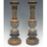 A pair of Doulton Lambeth candlesticks, incised with stiff leaves in tones of blue, tan and olive,