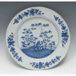 An 18th century Delft charger, decorated in underglaze blue with fence, peony and bamboo, deep