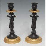 A pair of bronze and gilt metal figural candlesticks, everted leafy drip pans, classical lady