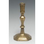 An early 18th century French brass candlestick, panelled sconce, knopped stem, stepped canted square