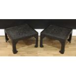 A pair of Chinese black cinnabar lacquer rounded square low tables, decorated in relief with