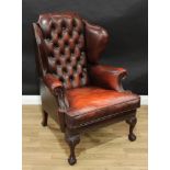 A George II style 'Chesterfield' wingback armchair, stuffed over upholstery, deep-button back, squab