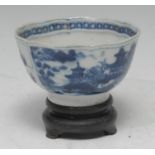 A Chinese circular wine cup, painted in tones of underglaze blue with pagodas and landscapes, within