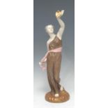 A Royal Worcester figure, Liberty, she stands holding a dove aloft, wearing flowing brown robes,