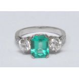 A diamond and Colombian emerald trilogy ring, central rectangular octagonal cut emerald, measuring