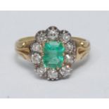 A diamond and emerald cluster ring, central octagonal cut emerald, surrounded by a band of ten old