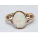 An opal solitaire ring, oval cabochon opal approx 11mm x 8mm, flashing strong green, blue and red