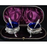 A pair of Victorian silver cauldron salts, chased with flowers and scrolling foliage, pad feet,