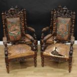 A set of four Victorian Baronial walnut armchairs, each boldly carved with a shaped cresting centred