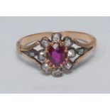 A diamond and ruby cluster ring, central oval vibrant red ruby surrounded by eight old cushion and