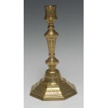 An early 18th century French brass octagonal candlestick, chased with swags, bell-husks and diapers,