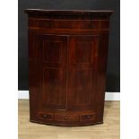 A George IV mahogany bow-fronted wall hanging corner cupboard, stepped cornice above a pair of