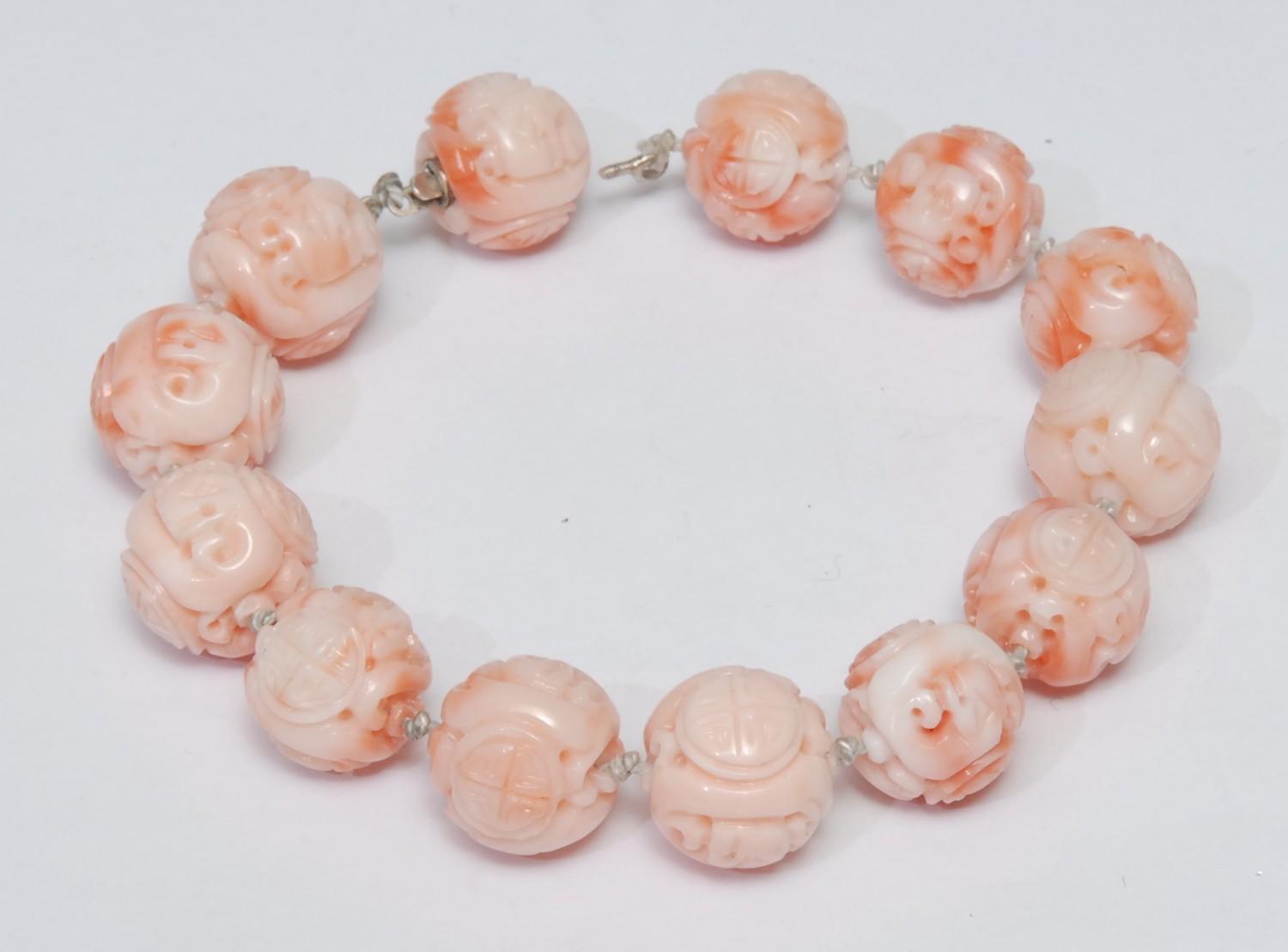 A Chinese carved pink bead bracelet, thirteen carved globular beads, decorated with Chinese