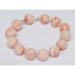 A Chinese carved pink bead bracelet, thirteen carved globular beads, decorated with Chinese