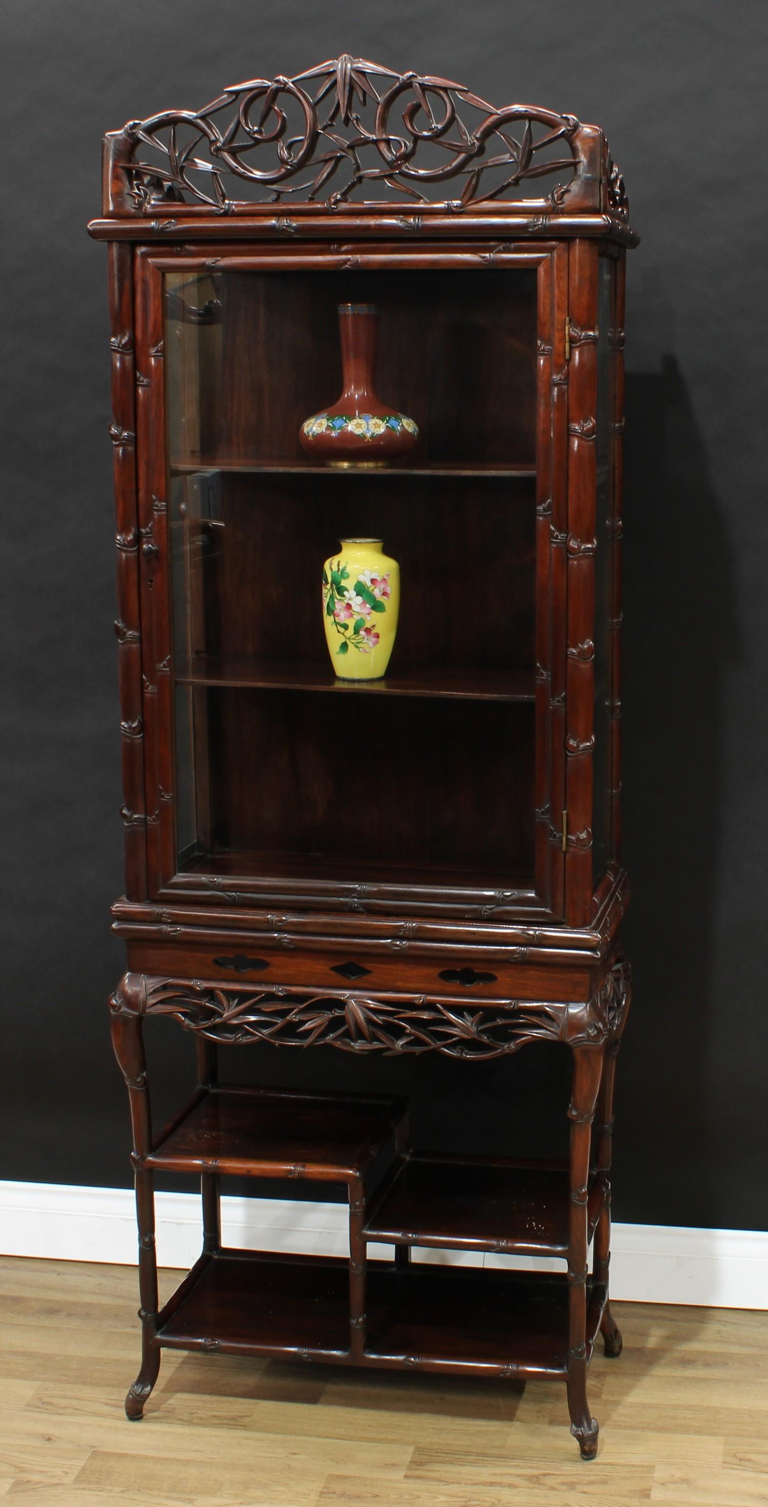 A Chinese hardwood vitrine on stand, shaped cresting above a rectangular door and an asymmetrical